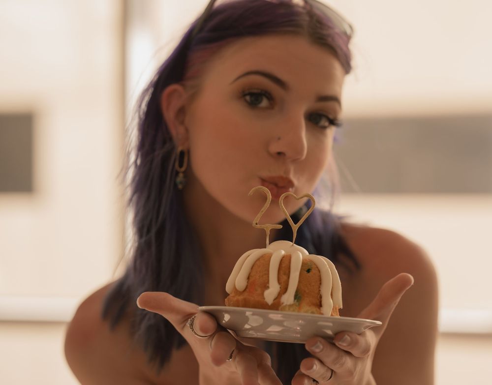 A person eating noodles from a bowl in a warm-lit setting.
