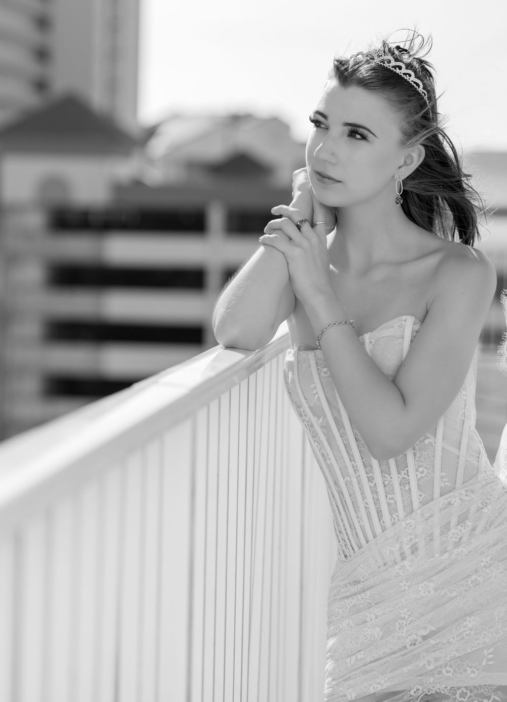 A black and white artistic bridal portrait series showing a woman in a wedding dress leaning on a white railing.