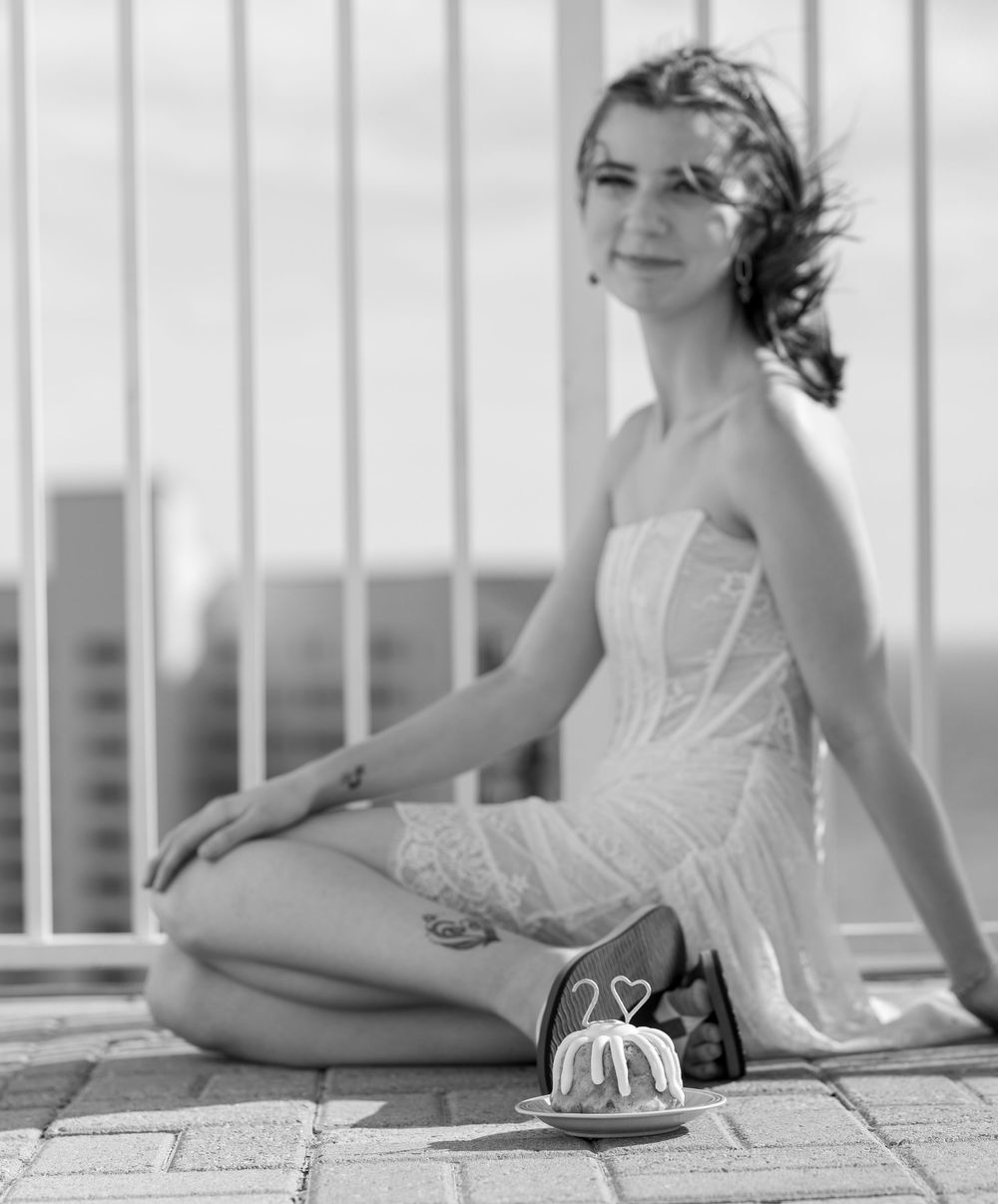 Black and white series of someone in a white dress reclining on a patio with decorative railings.