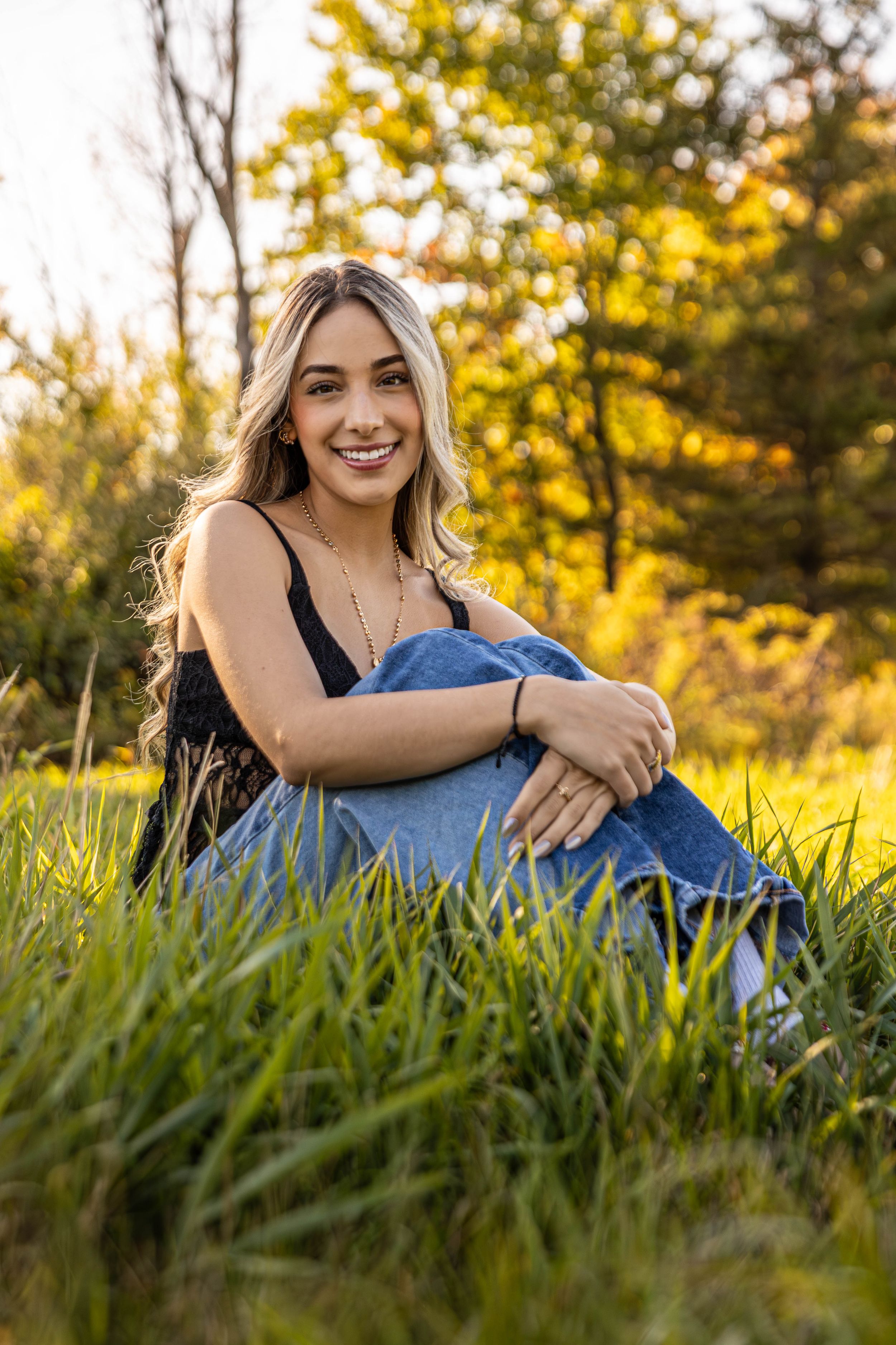 Outdoor portrait session in tall grass during golden hour sunset.