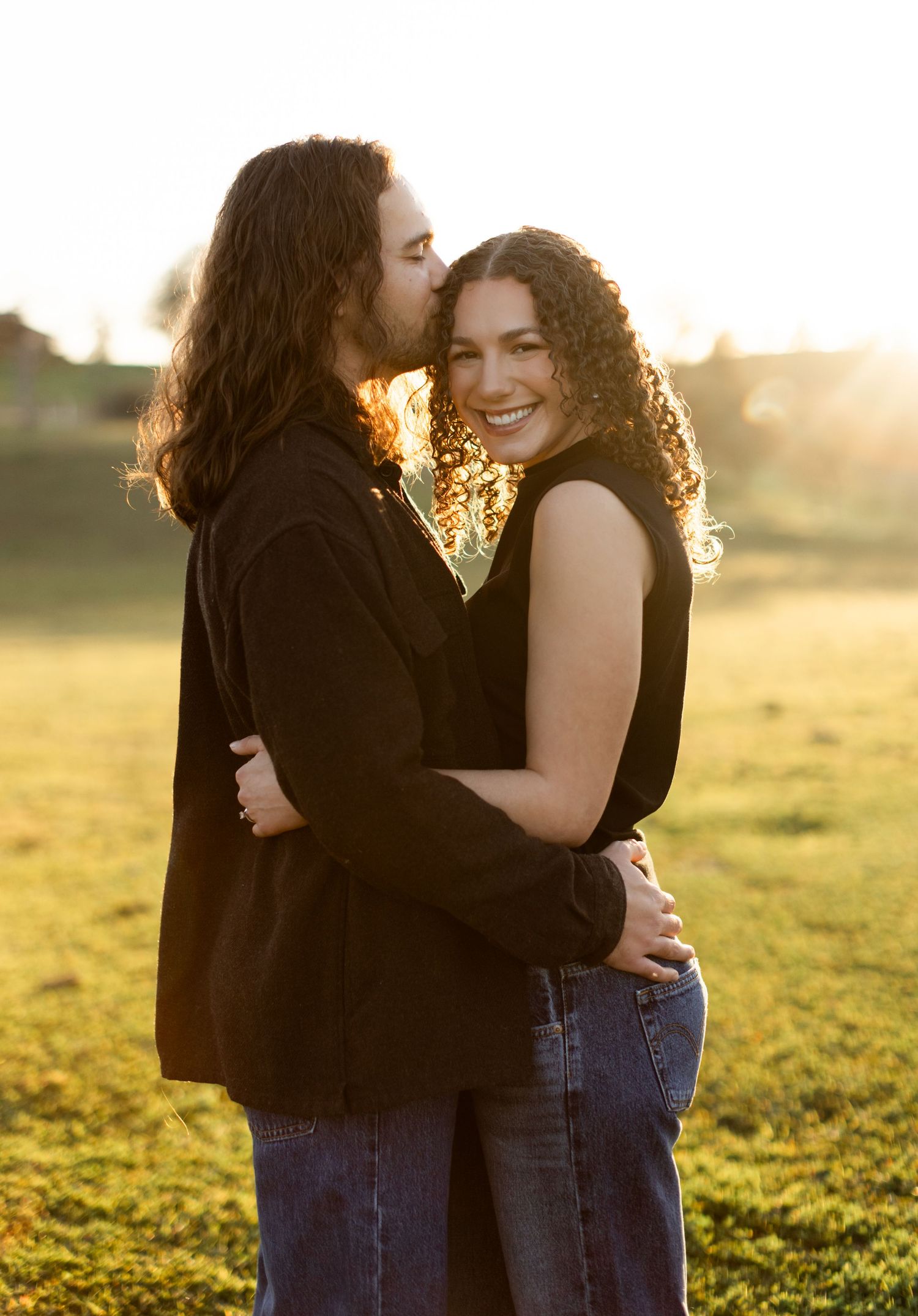Intimate moment between couple sharing affection in warm evening sunlight.