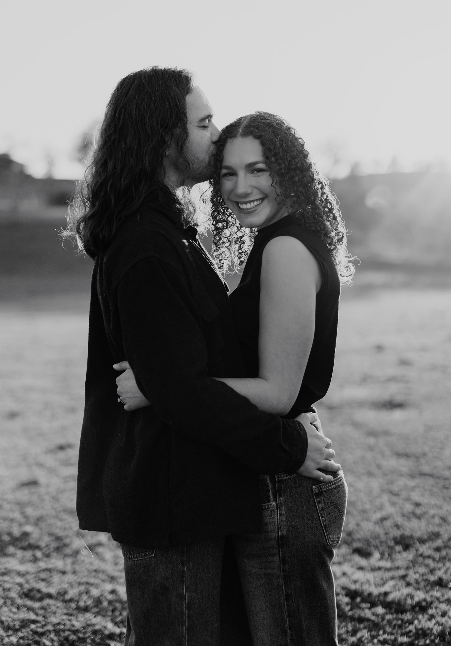 Black and white photo series showing an intimate couple embracing in a field at sunset.