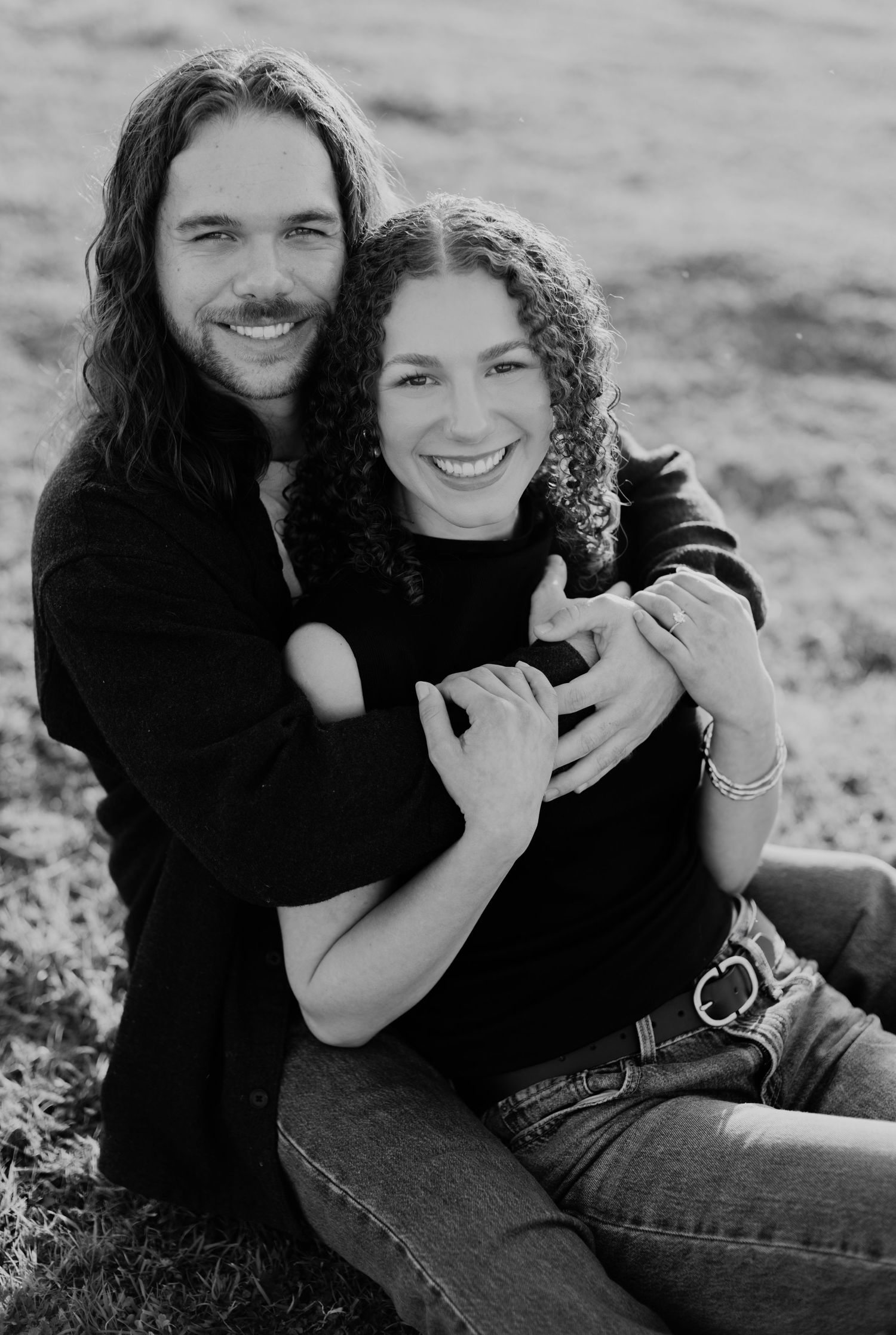 Black and white photo series of a couple embracing and laughing together outdoors.