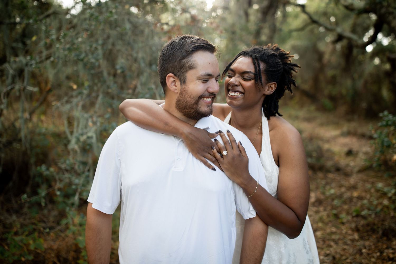 Couple in white outfits share playful romantic moments during an outdoor photoshoot.