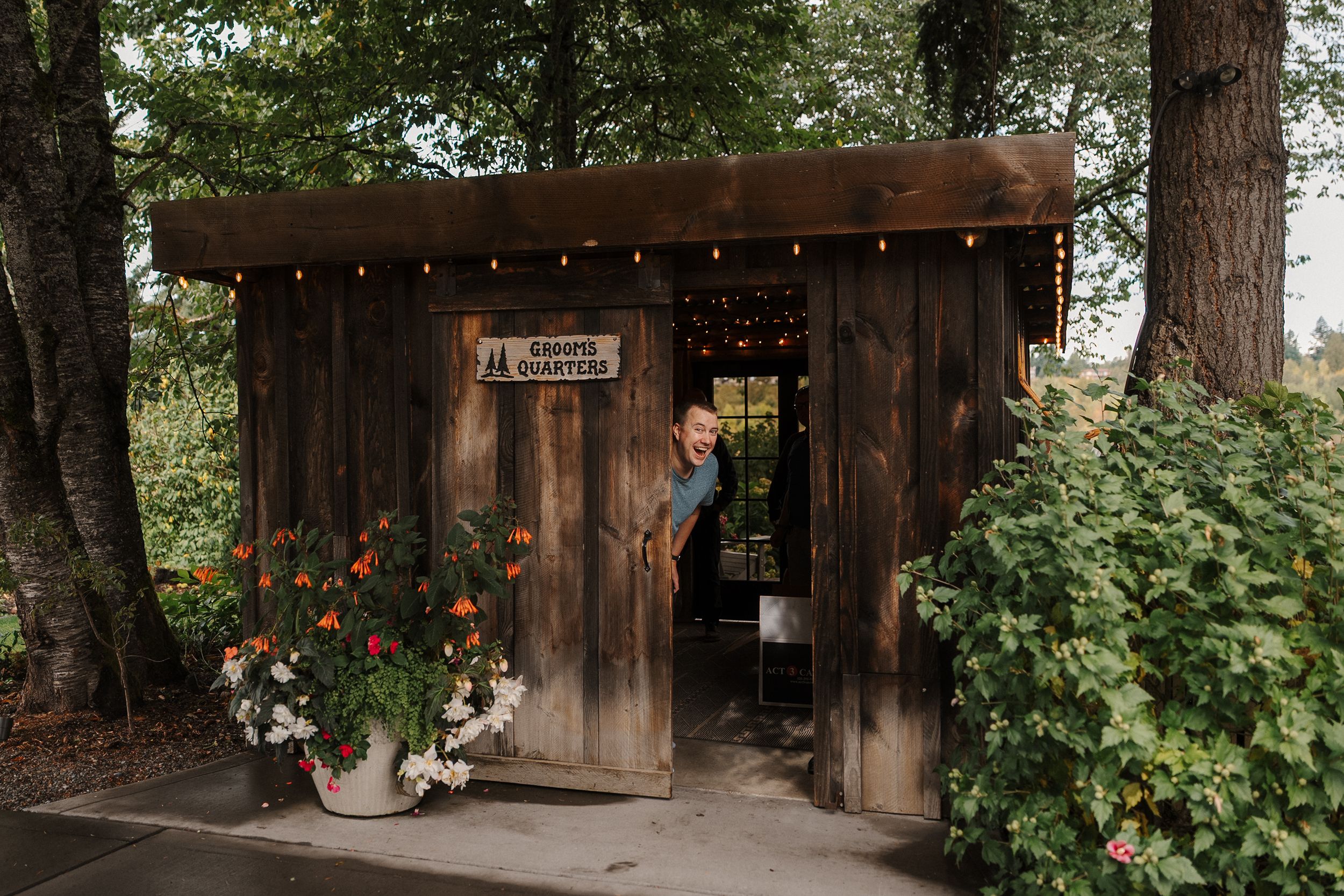 Rustic wooden cabin nestled among tall trees in a forest setting with natural landscaping and outdoor lighting.