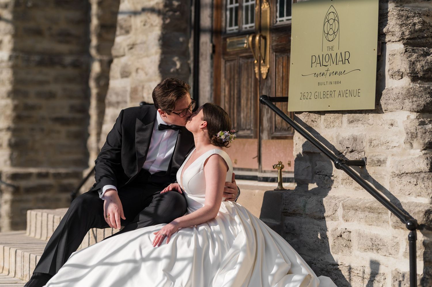 A couple in wedding attire shares a romantic moment under stone archways during their wedding photoshoot.