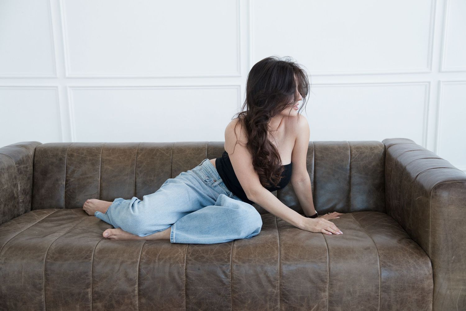 Person lying on a gray couch in various relaxed positions showing signs of depression and fatigue.