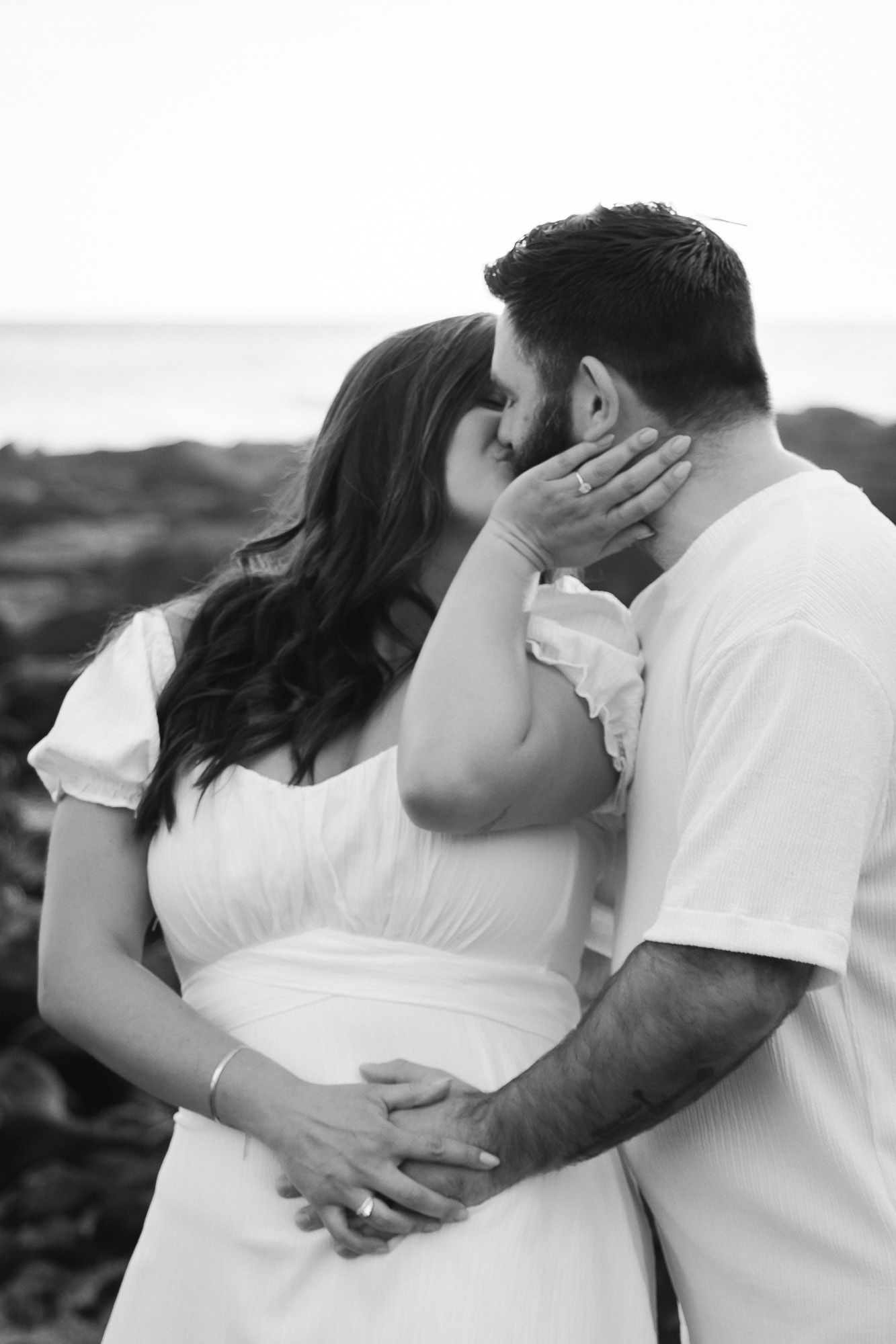 A man has his arm around his girlfriend as she snuggles into his cheek, her hand on his other cheek.