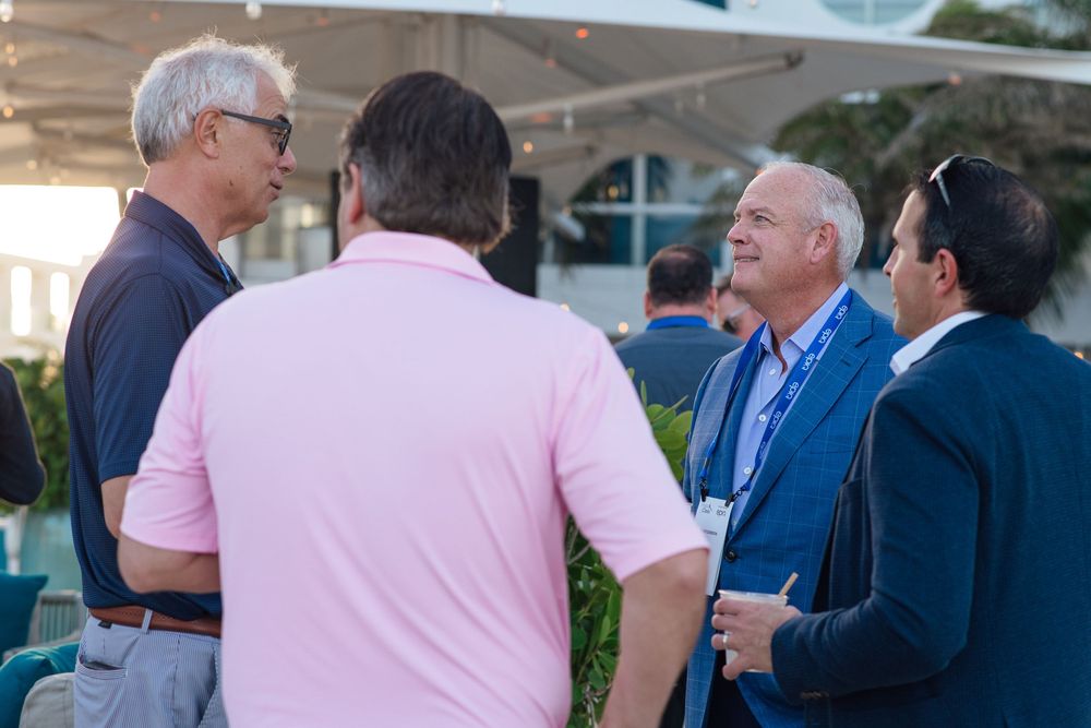 Group of professional men networking and conversing at an outdoor business conference event.