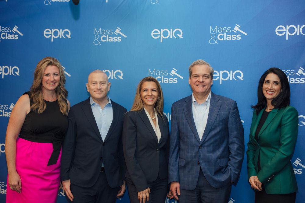 Five professionals posing together in front of Epiq and Mass and Class branded backdrop.