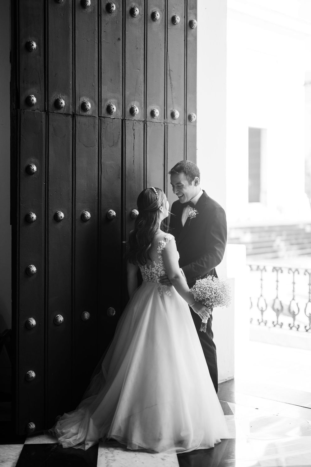 Black and white portrait of bride and groom at entrance of Hotel El Convento during cocktail hour