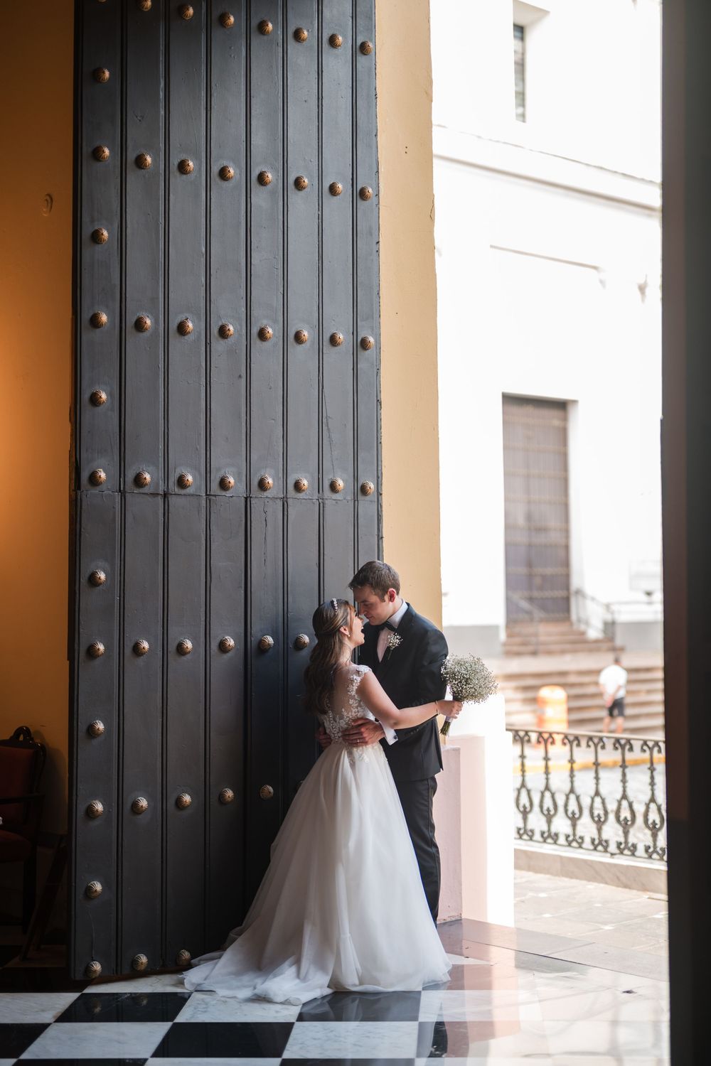 Bride and groom embracing near historic doorway during cocktail hour at Hotel El Convento