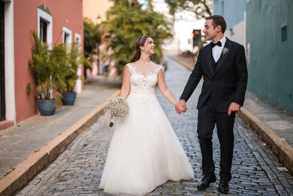 Bride and groom holding hands while walking on cobblestone street during cocktail hour in Old San Juan
