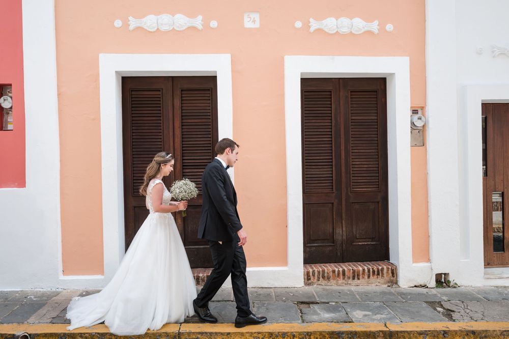 Bride and groom walking past pastel buildings during cocktail hour in Old San Juan