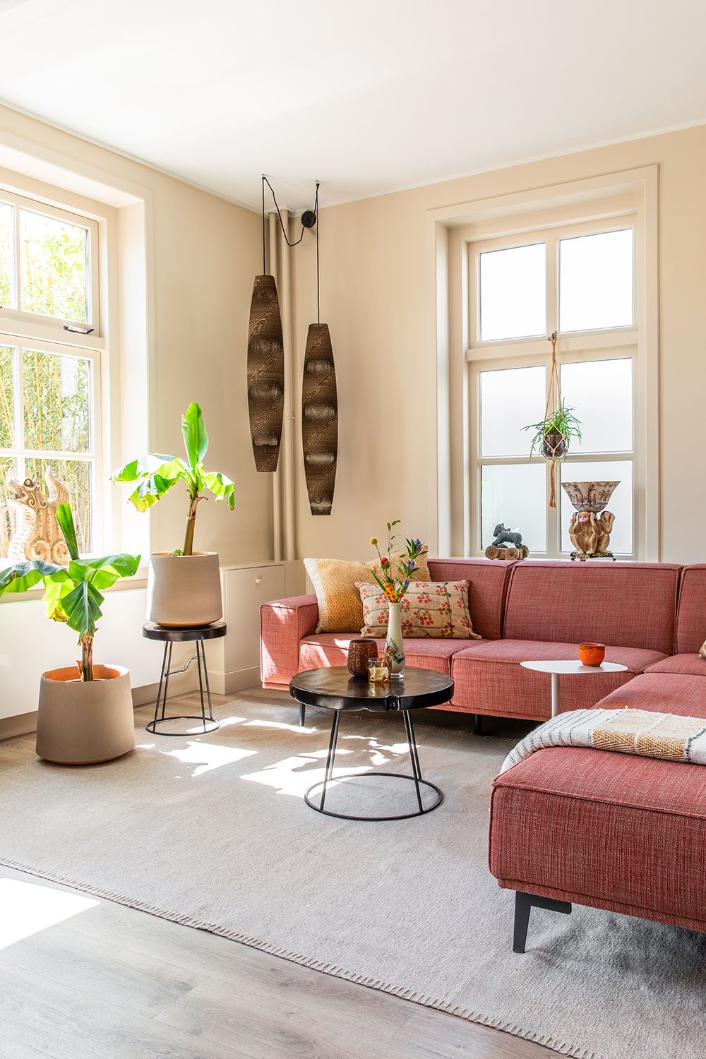 Een interieurfoto van een kleurrijk interieur met lichte frisse kleuren en een rode bank met een eclectische sfeer.