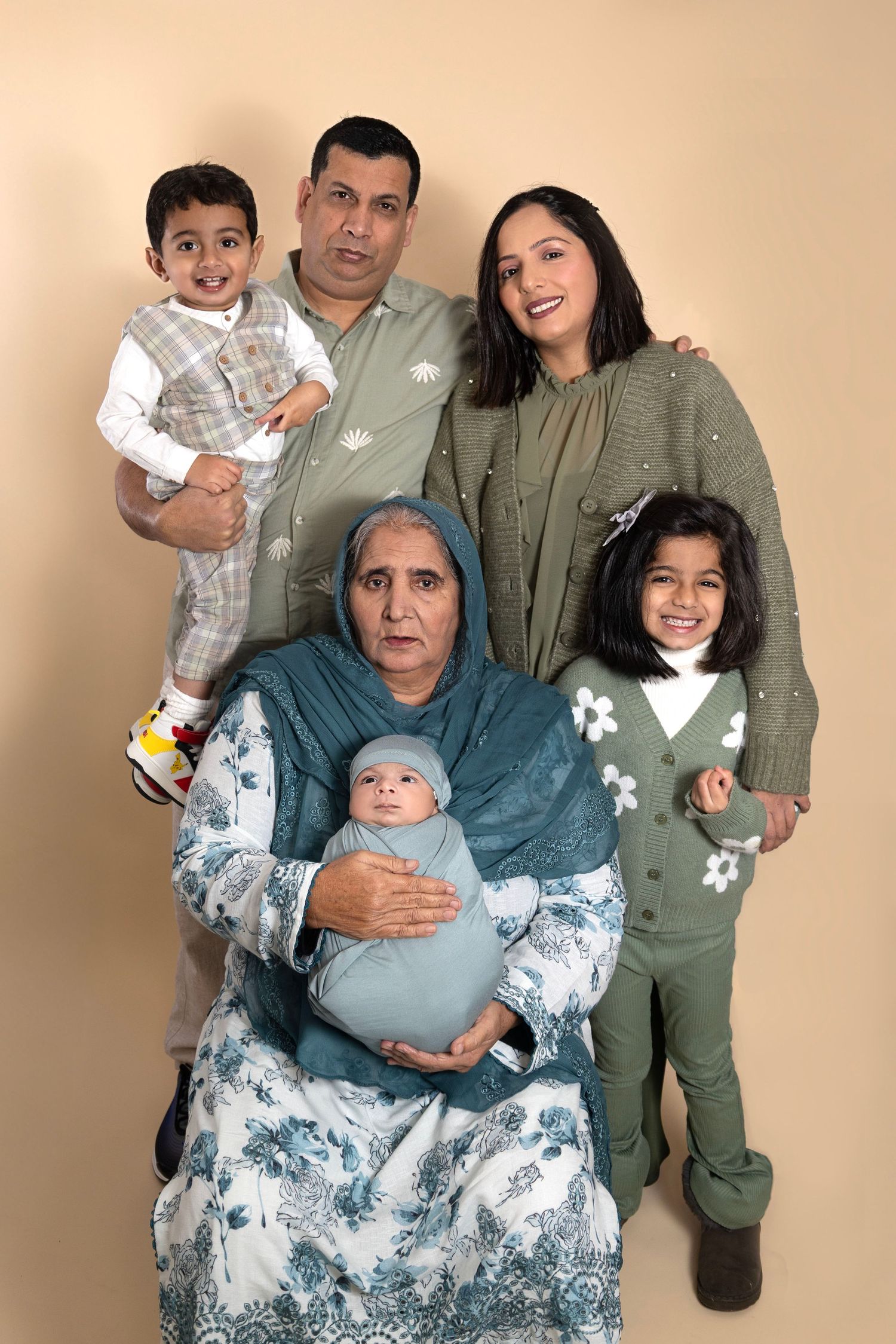 A family wearing coordinated blue and grey outfits poses together in a series of four professional studio portraits.