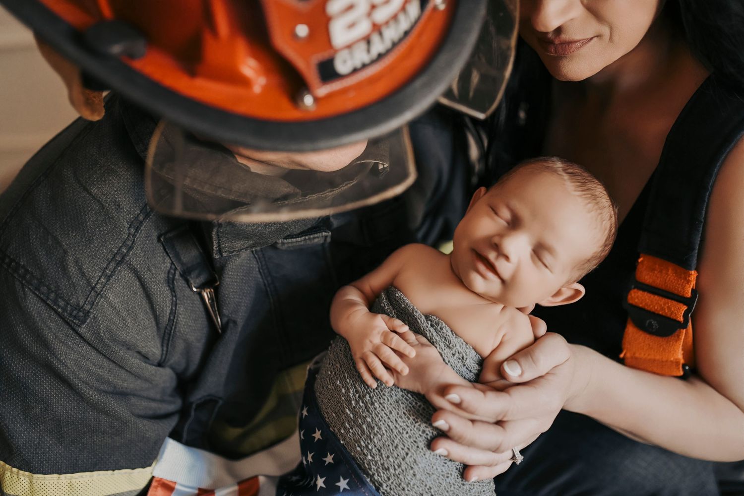 Dad firefighter gently holding his newborn baby during an emotional studio newborn session in the DFW area