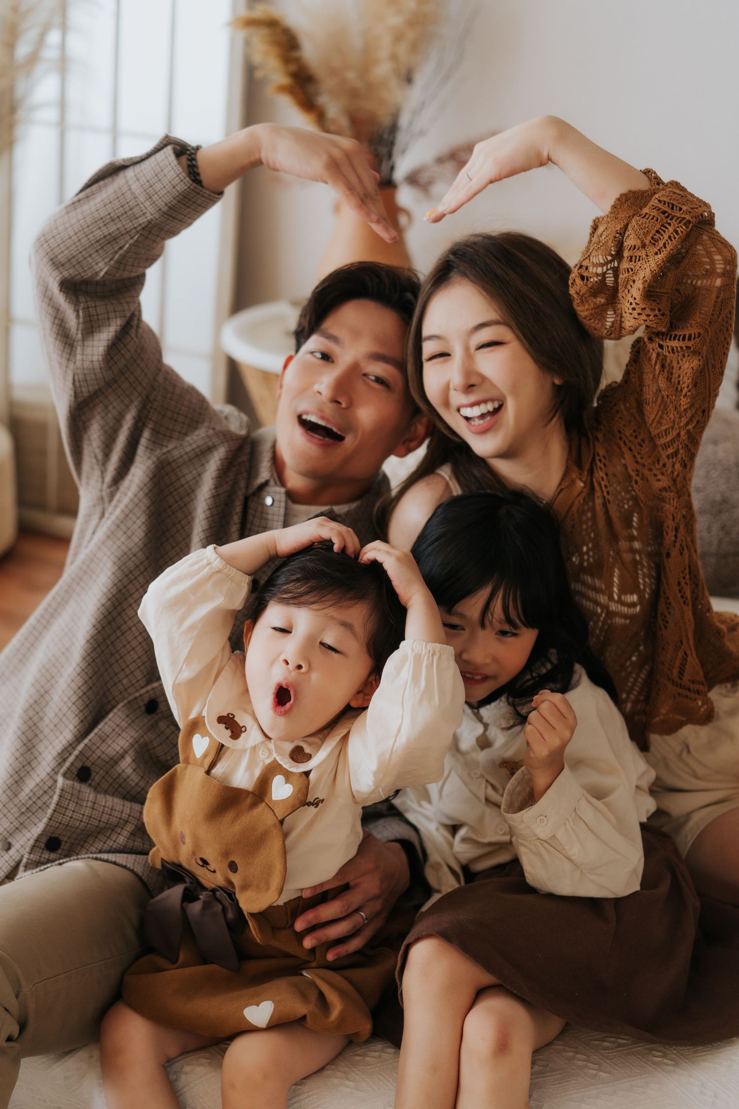 A joyful family sharing a candid moment together while sitting and laughing on the floor at home.一家人其樂融融地坐在家裡的地板上，開懷大笑，分享著溫馨的瞬間。