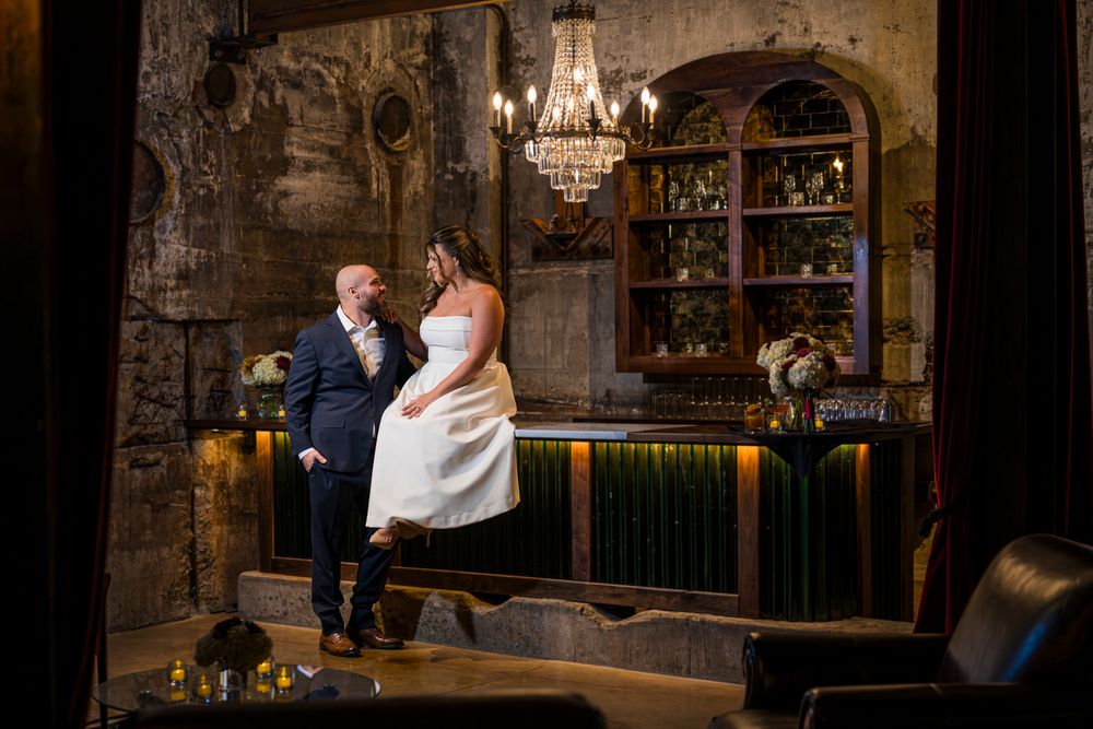 Couple shares intimate moments in rustic stone venue with warm lighting and vintage decor.