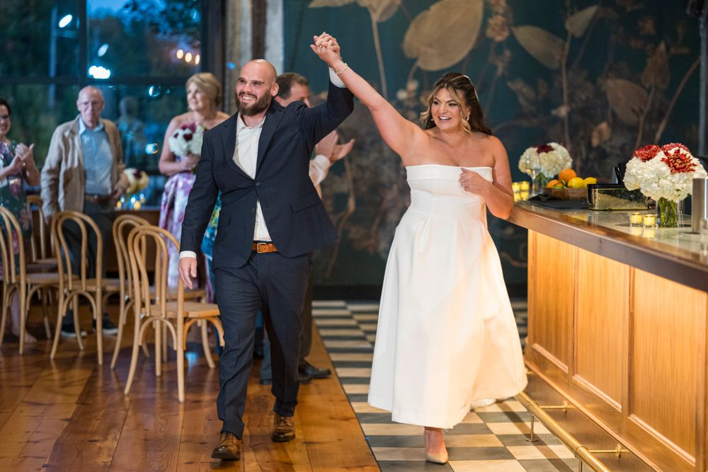 A wedding couple shares their first dance together on a wooden dance floor at their reception celebration.