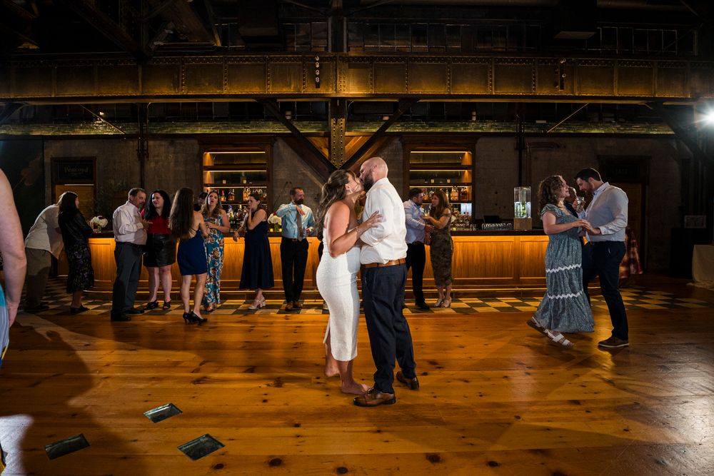 People dancing together in a warmly lit rustic barn venue during a celebration event.