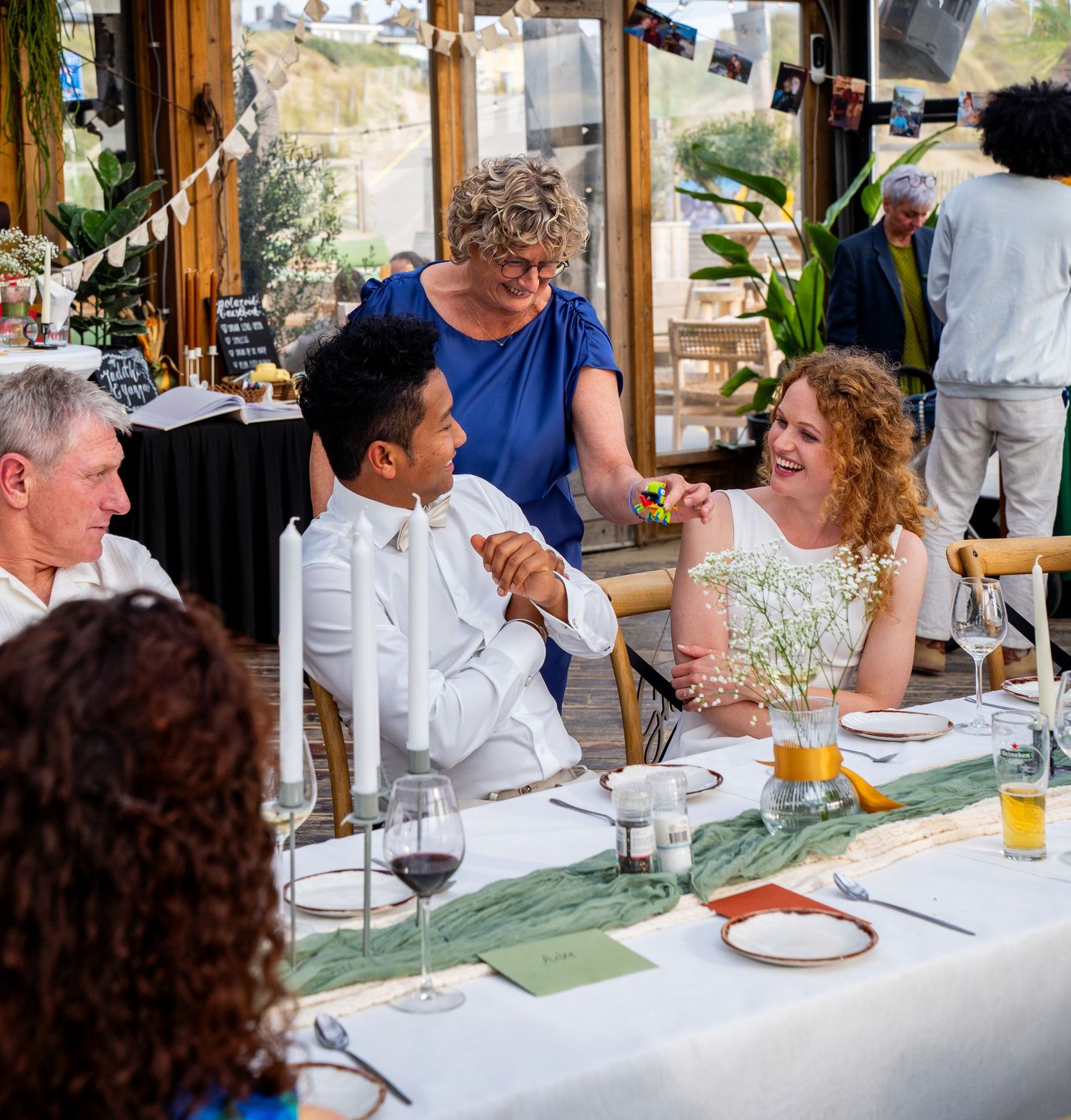 Bruid en bruidegom lachen met gasten aan een elegant gedecoreerde tafel tijdens het huwelijksdiner. emotinele moeder