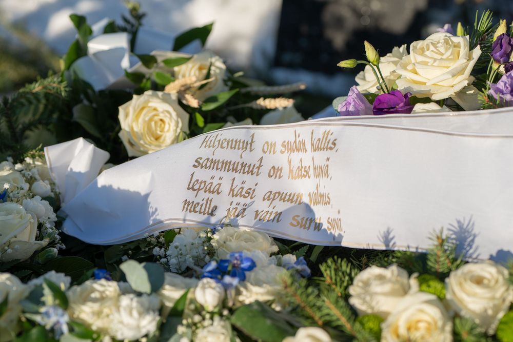 Hautajaiskuvausta Kalajoella, omaisten kauniit tekstit kukkalaitteissa.
