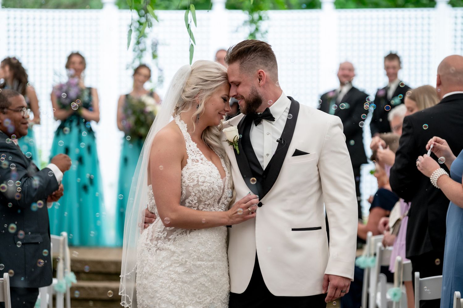 A couple shares their first dance at an outdoor wedding reception while guests watch and take photos.