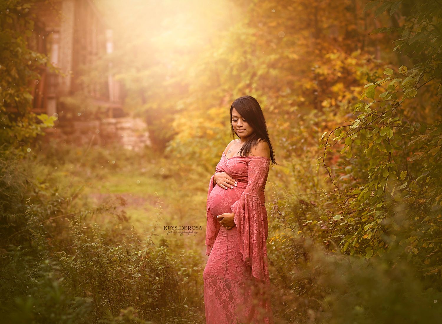A figure in a flowing pink dress stands in a sunlit autumn garden with golden bokeh effects.