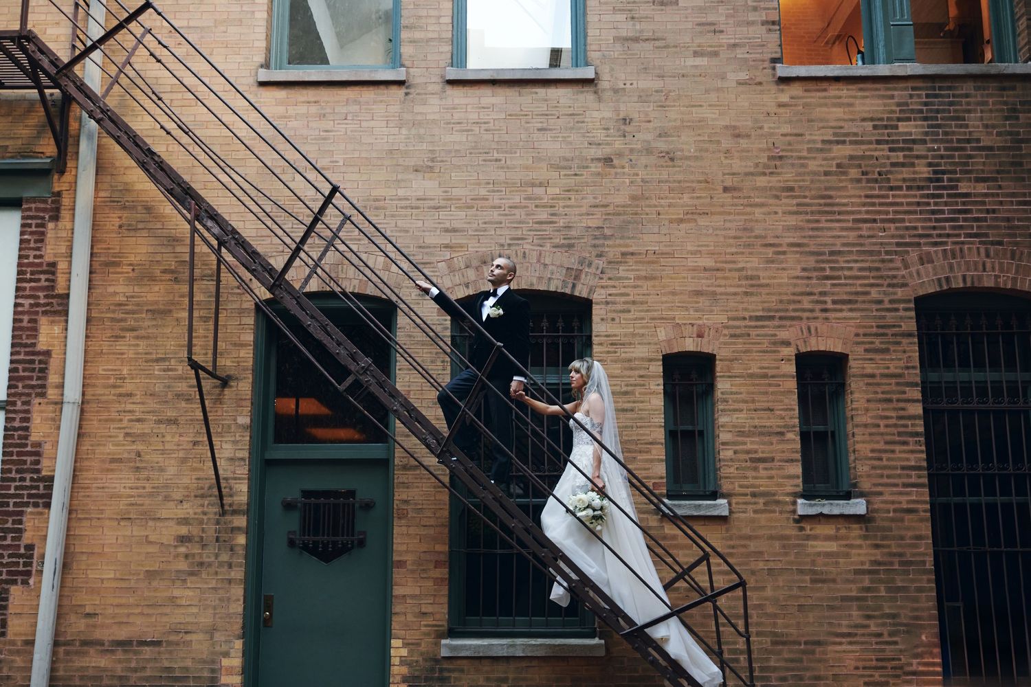 Vintage brick apartment building exterior with fire escapes and windows on a sunny day in New York City.