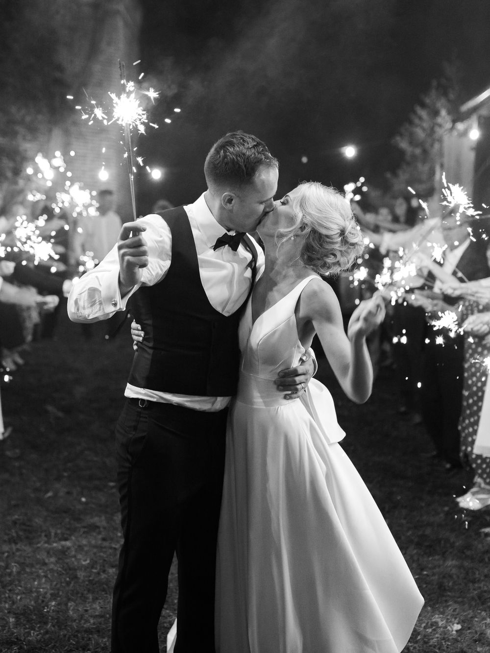 Newlyweds share an intimate moment while holding sparklers during their evening celebration.