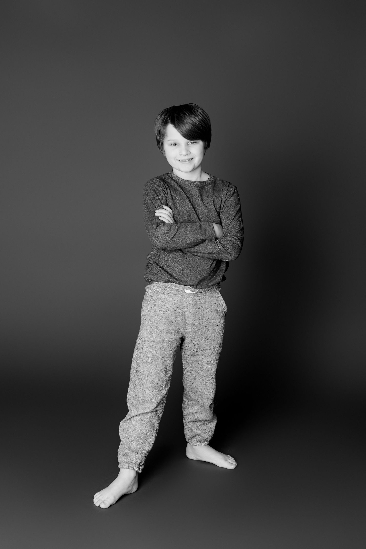 Black and white photo series showing a child in a dark sweater and gray pants striking different casual poses.