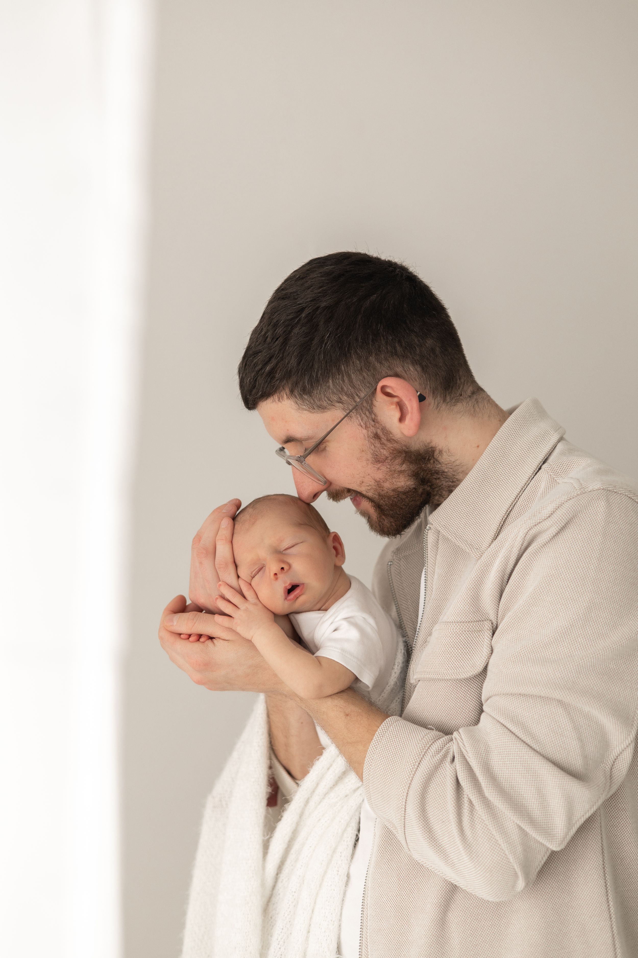 Newborn photographer Nottingham cosy home studio sleeping newborn baby held in dads arms