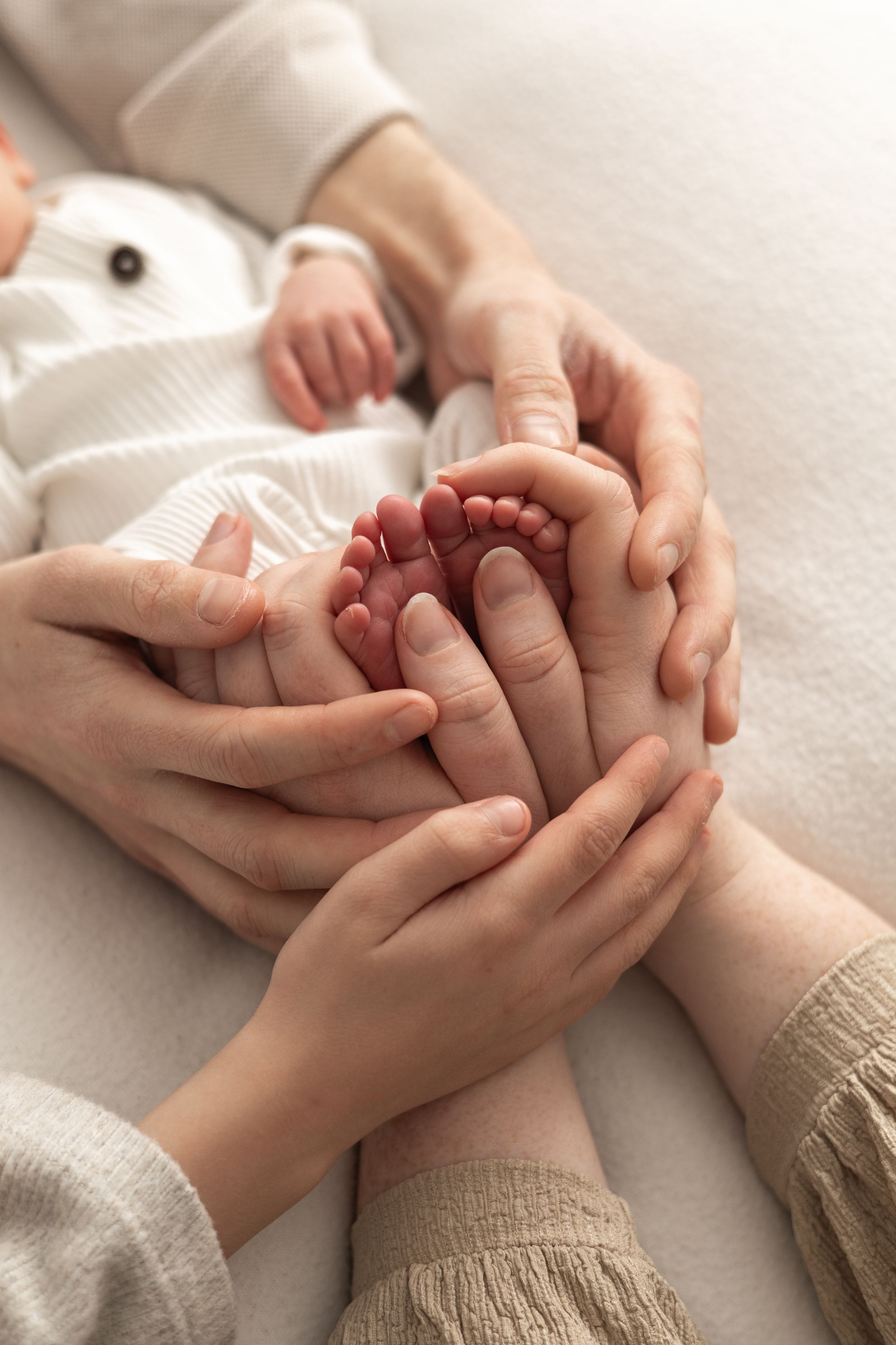 Newborn photography Nottingham parents tenderly cradling newborn baby feet in their hands