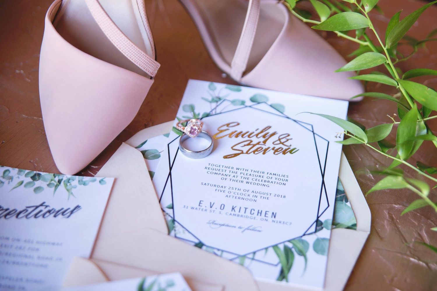 Lay flat photo of wedding rings, shoes and an invitation.