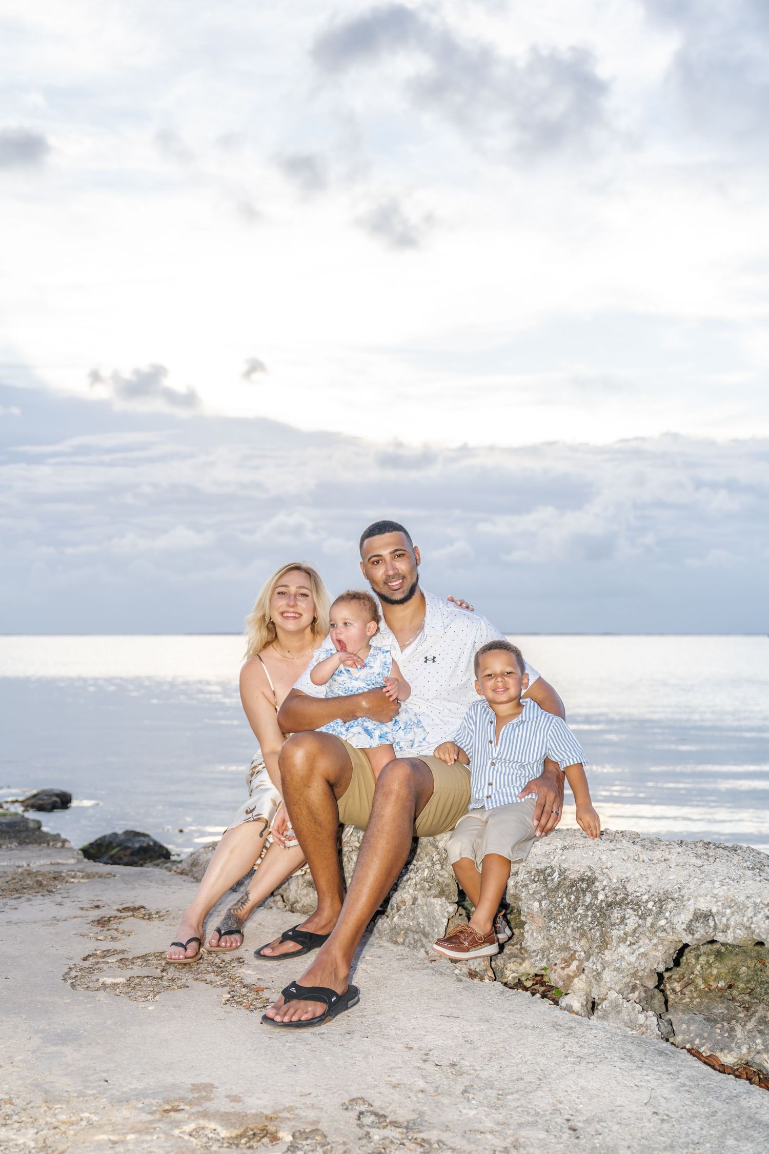 A family enjoying a relaxing moment together on rocky beach formations during sunset.