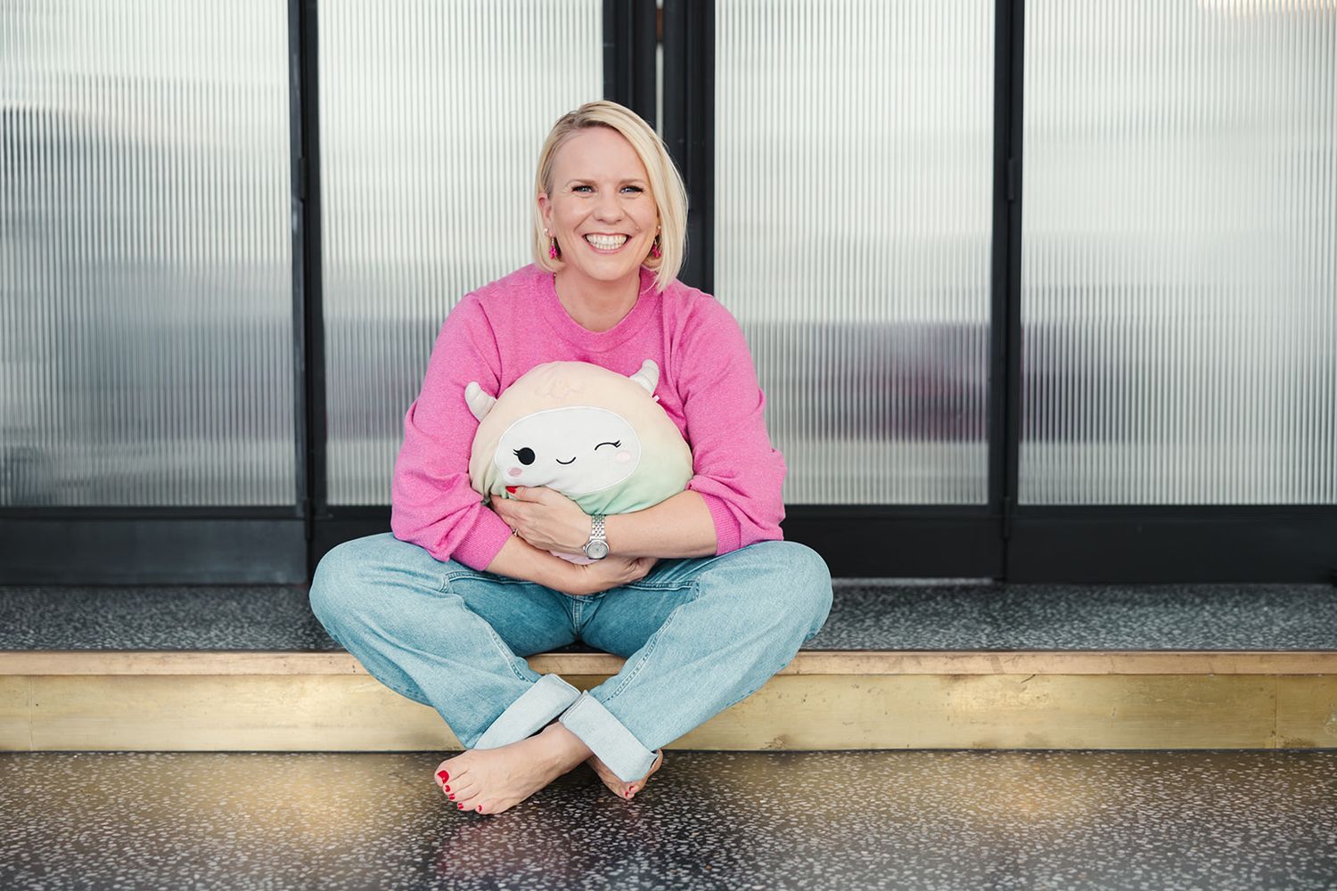 CEO happily sitting on the floor hugging a plushy