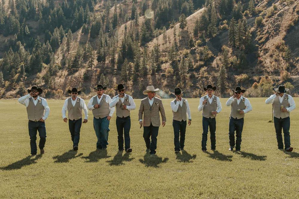Groomsmen in cowboy hats and taupe vests, sharing laughs before the ceremony at the American Homestead. Captured by a Spokane wedding photog