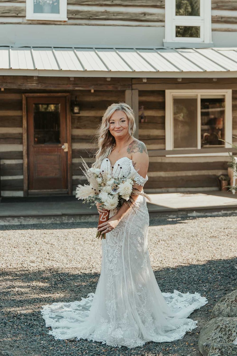 A candid moment of the bride in her boho country lace gown, holding a wildflower bouquet. Photographed by a Washington wedding photographer