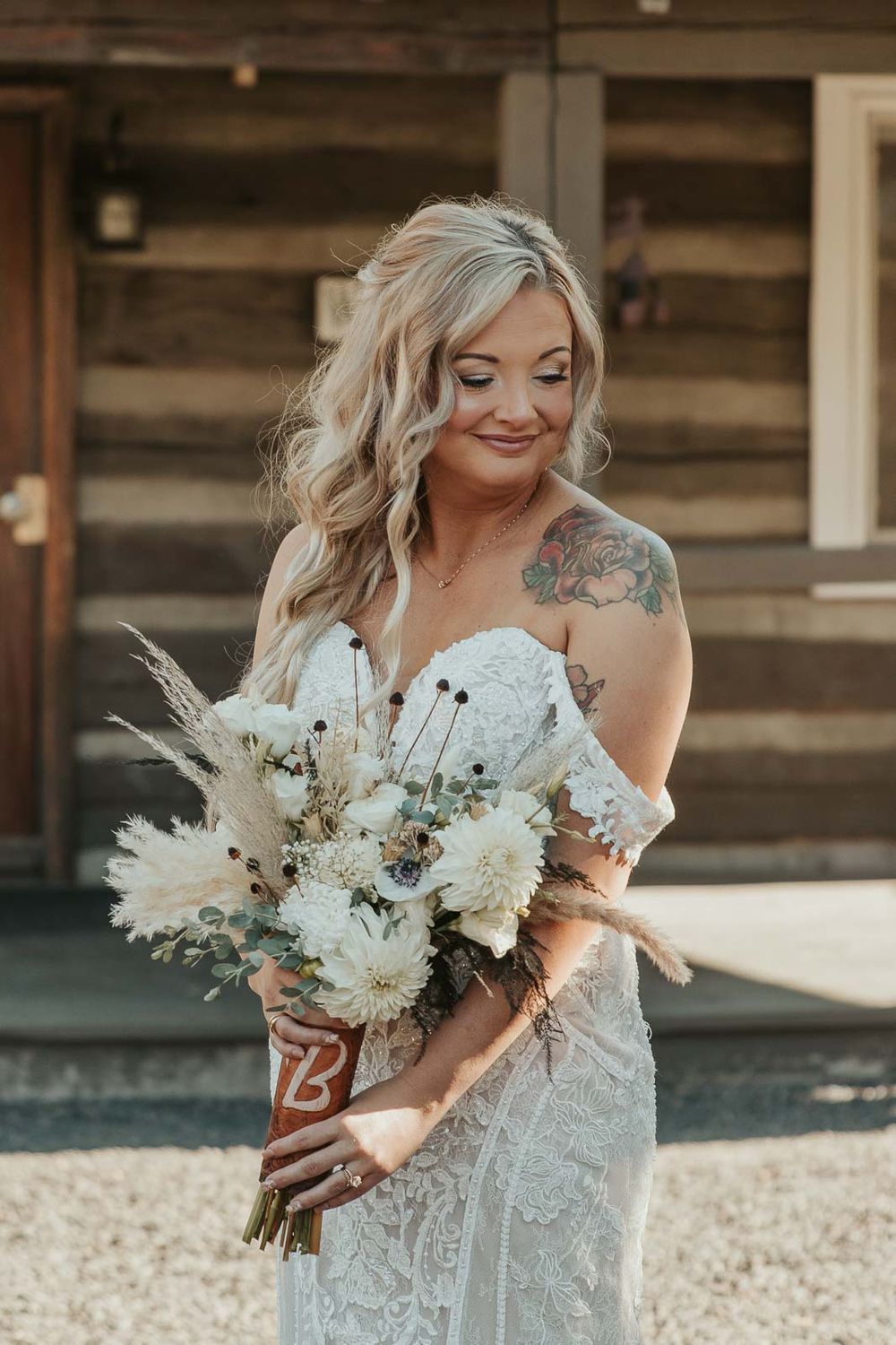 A candid moment of the bride in her boho country lace gown, holding a wildflower bouquet. Photographed by a Washington wedding photographer