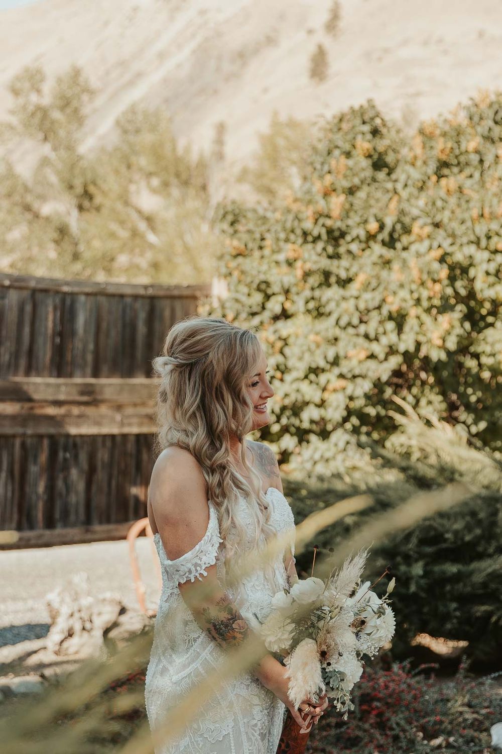 A candid moment of the bride in her boho country lace gown, holding a wildflower bouquet. Photographed by a Washington wedding photographer
