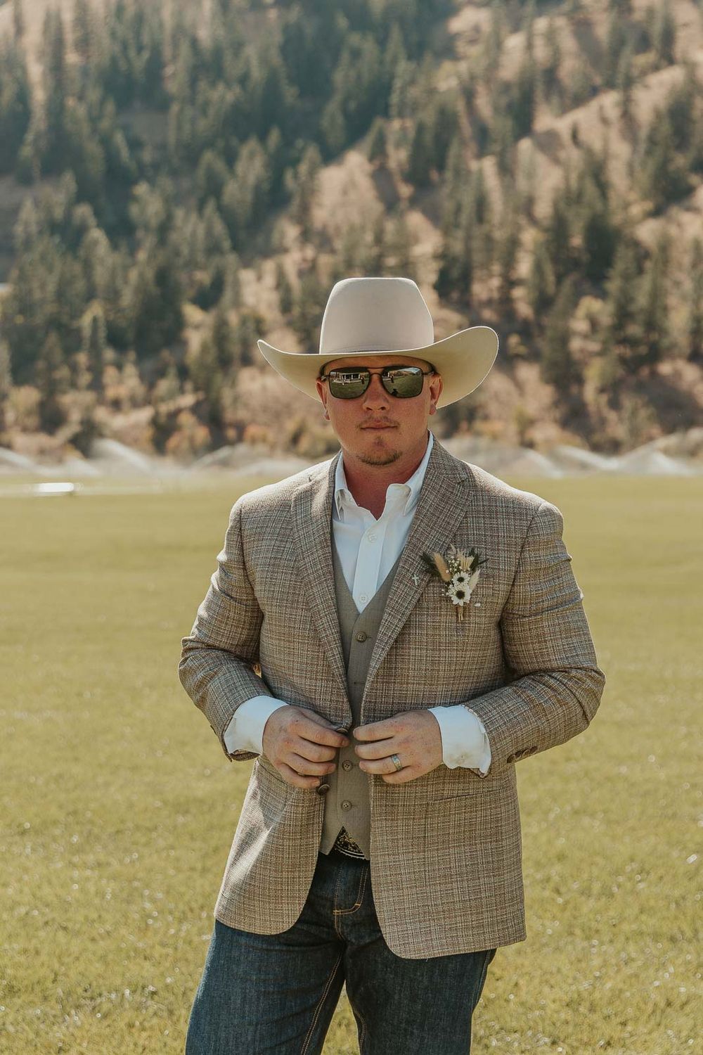 Groom Cody in a plaid jacket and cowboy hat at the American Homestead. Photographed by a Washington wedding photographer.