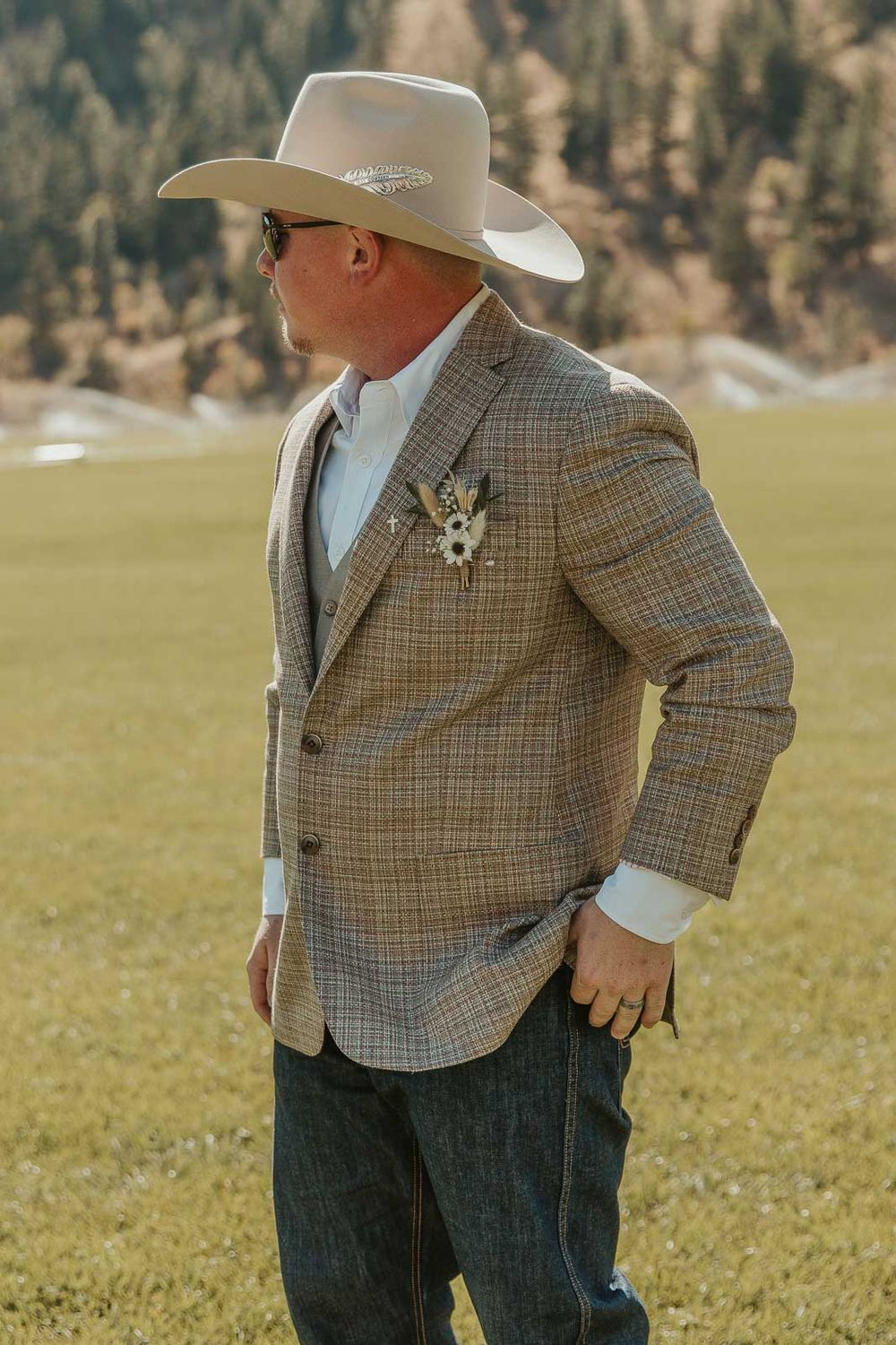 Groom Cody in a plaid jacket and cowboy hat at the American Homestead. Photographed by a Washington wedding photographer.