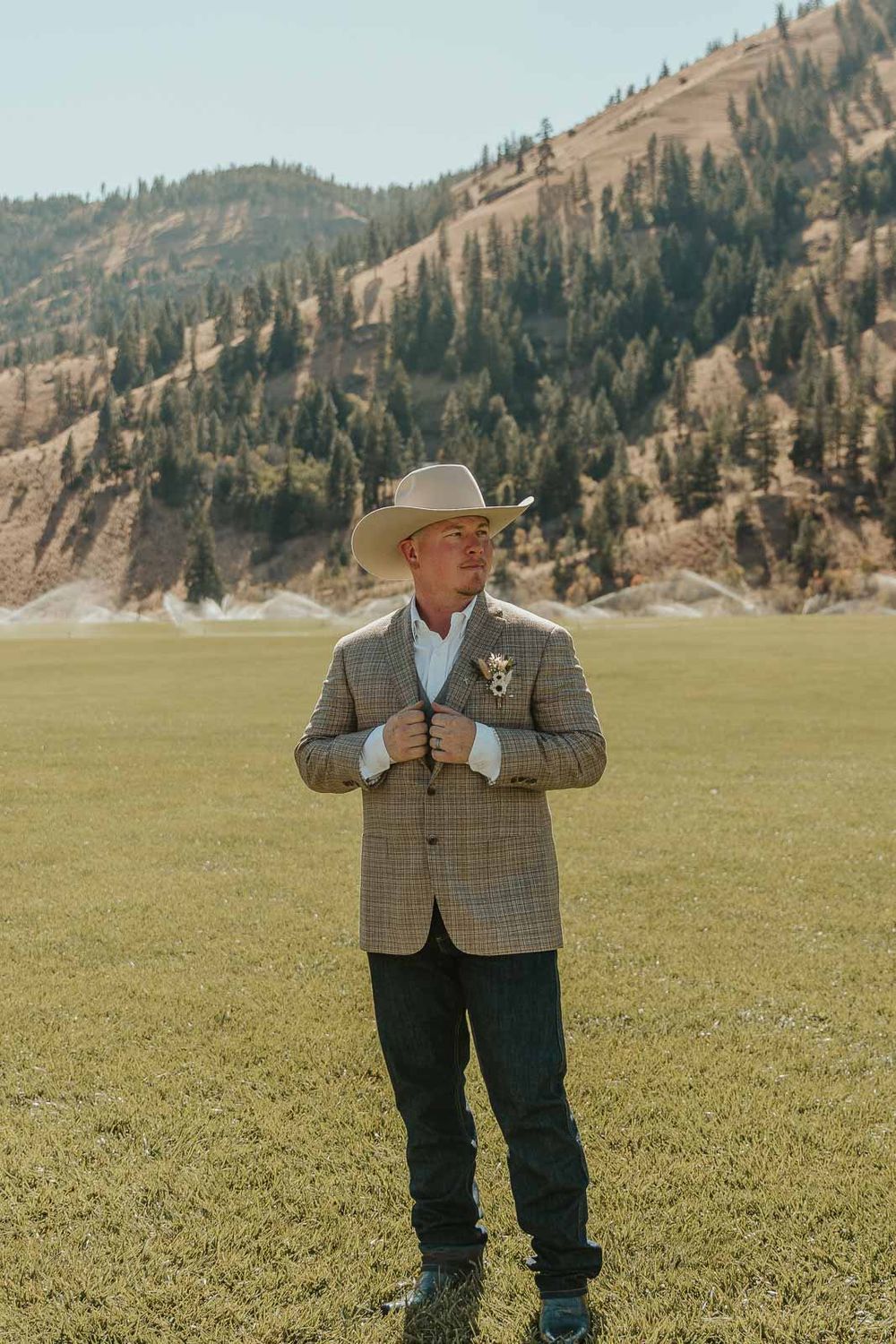 Groom Cody in a plaid jacket and cowboy hat at the American Homestead. Photographed by a Washington wedding photographer.