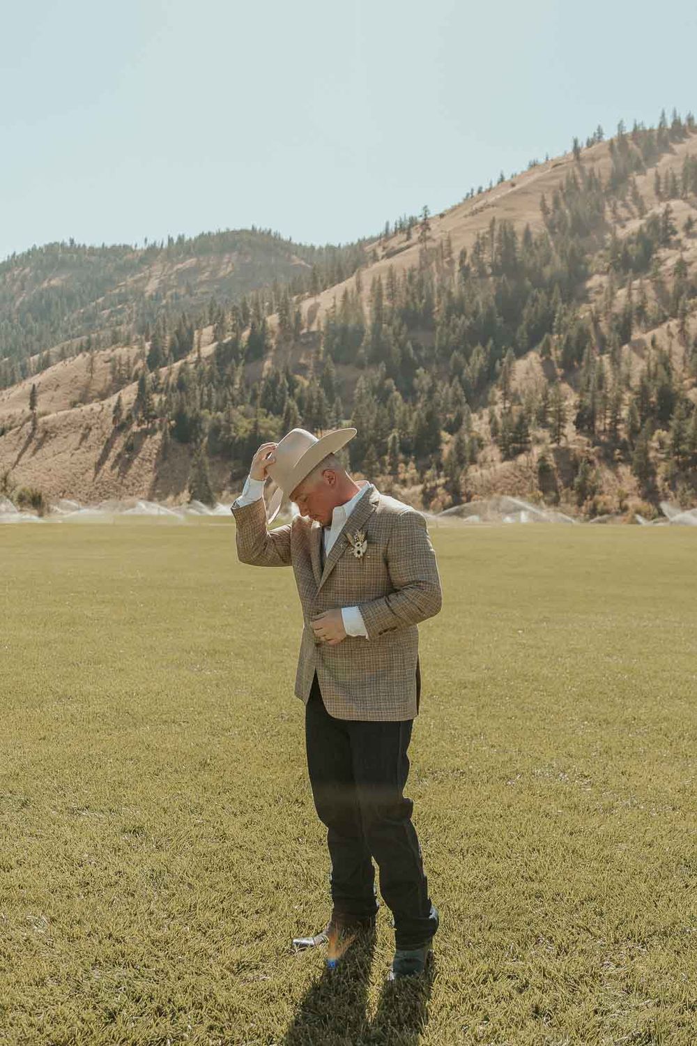 Groom Cody in a plaid jacket and cowboy hat at the American Homestead. Photographed by a Washington wedding photographer.