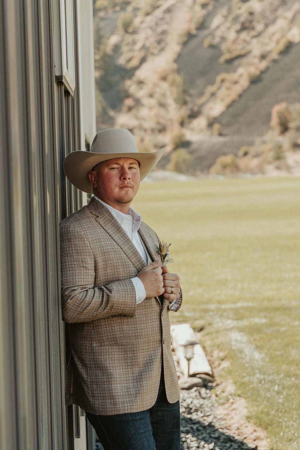 Groom Cody in a plaid jacket and cowboy hat at the American Homestead. Photographed by a Washington wedding photographer.