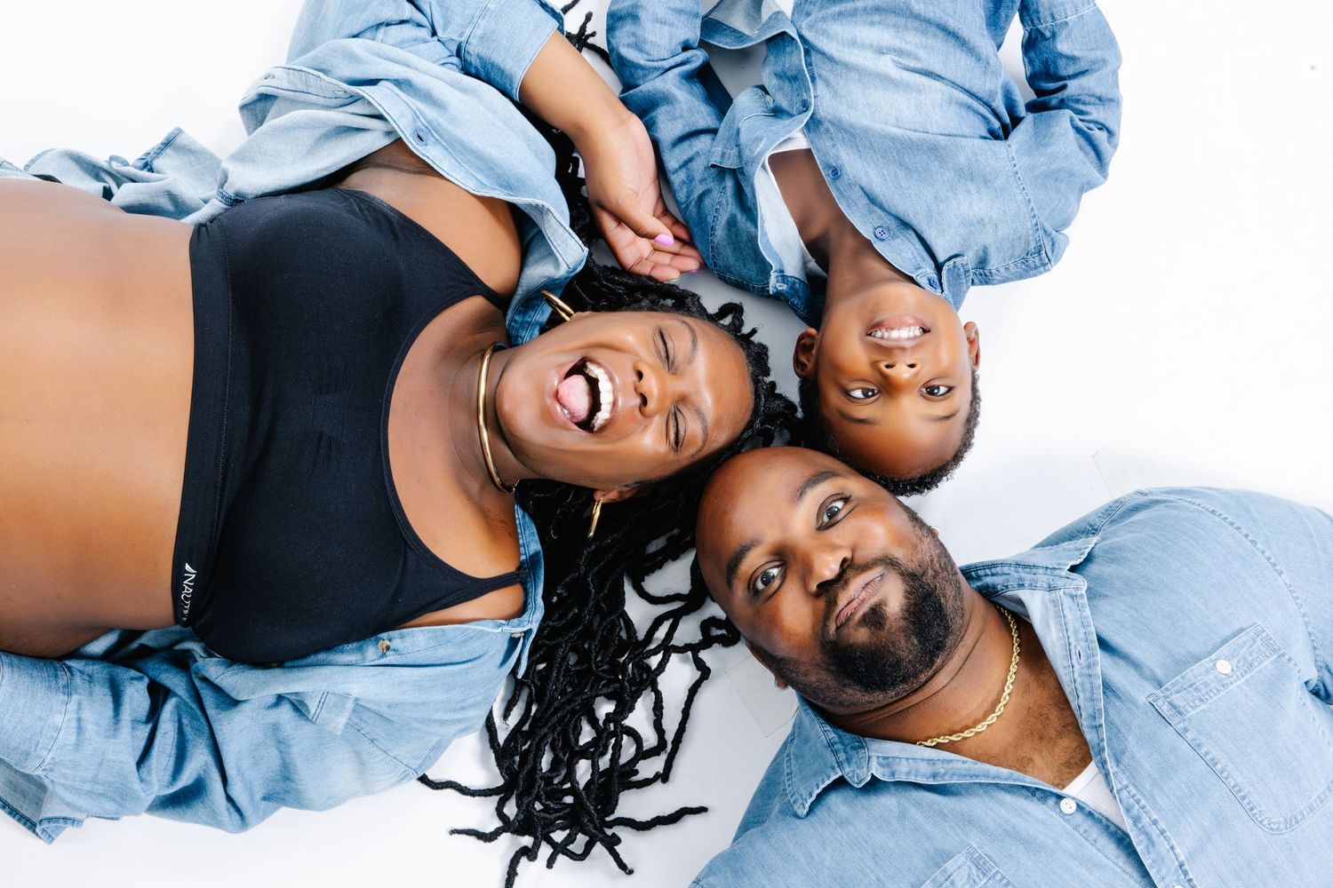 Group wearing matching denim outfits lying down together in playful portrait pose.