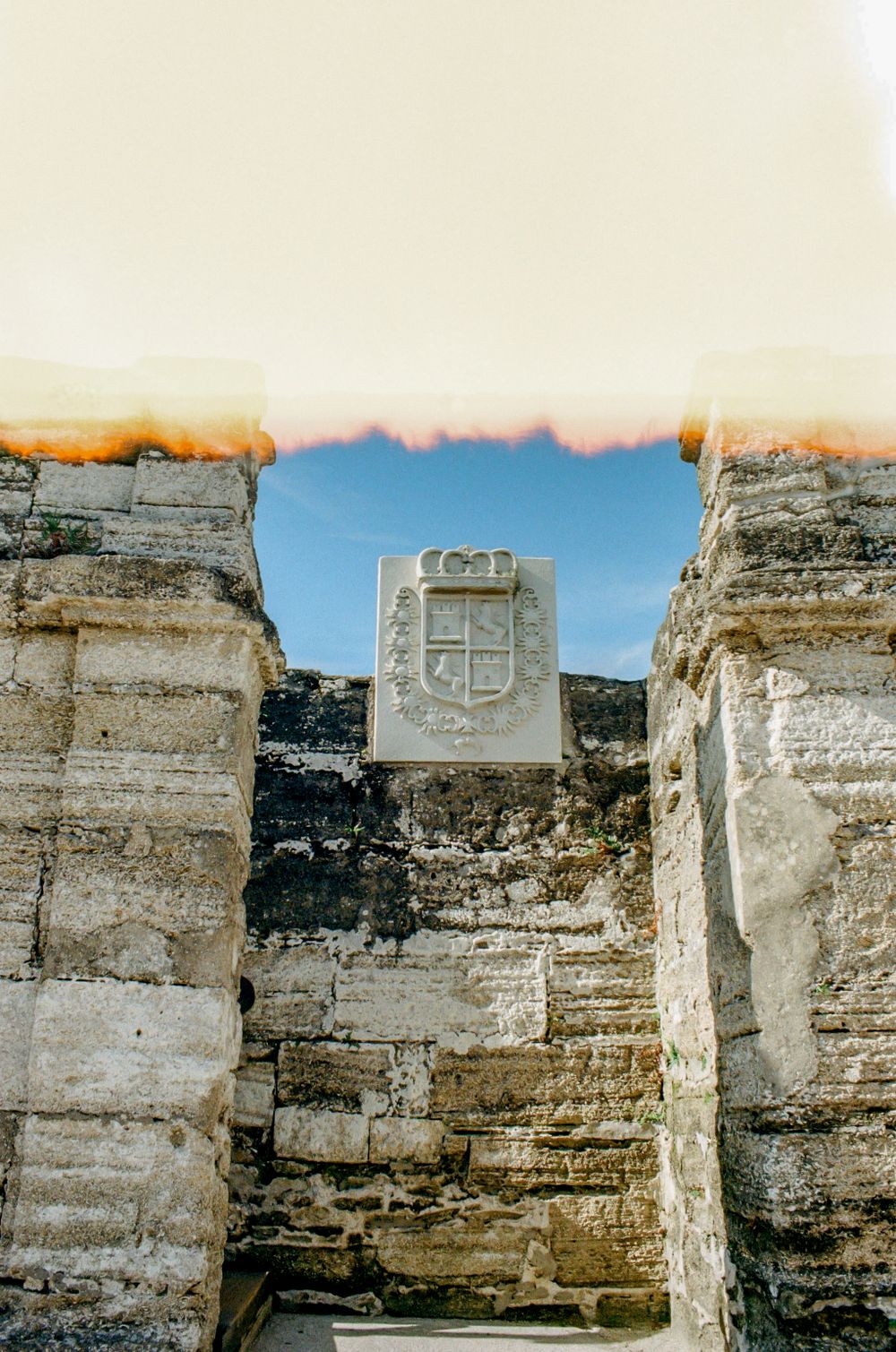 Ancient stone ruins with a carved heraldic shield visible between weathered walls.