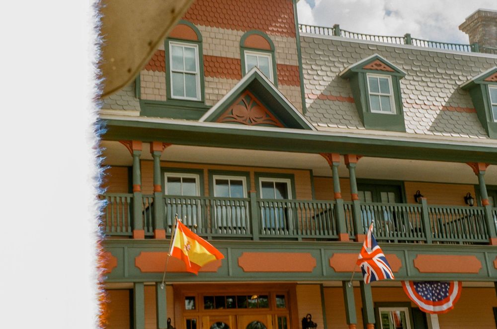 Victorian-style house with flags and decorative trim featuring a wraparound porch.