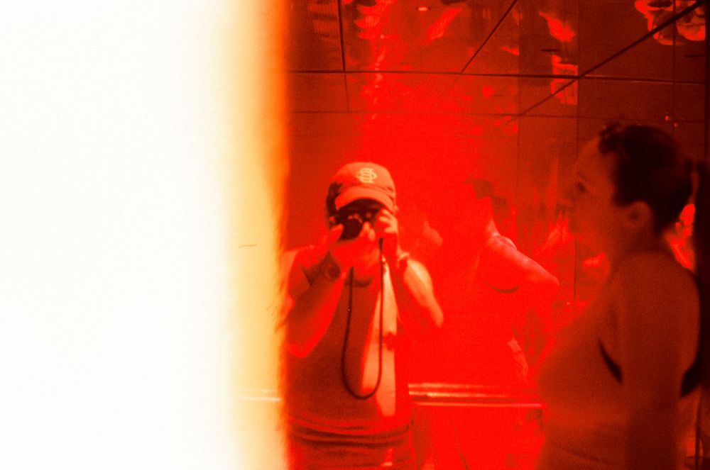 Abstract red-tinted photograph with light leaks and silhouettes.